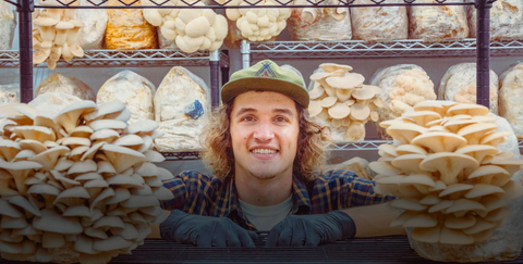Benjamin Deuling surrounded by mushrooms in SporeAttic's cultivation facility 